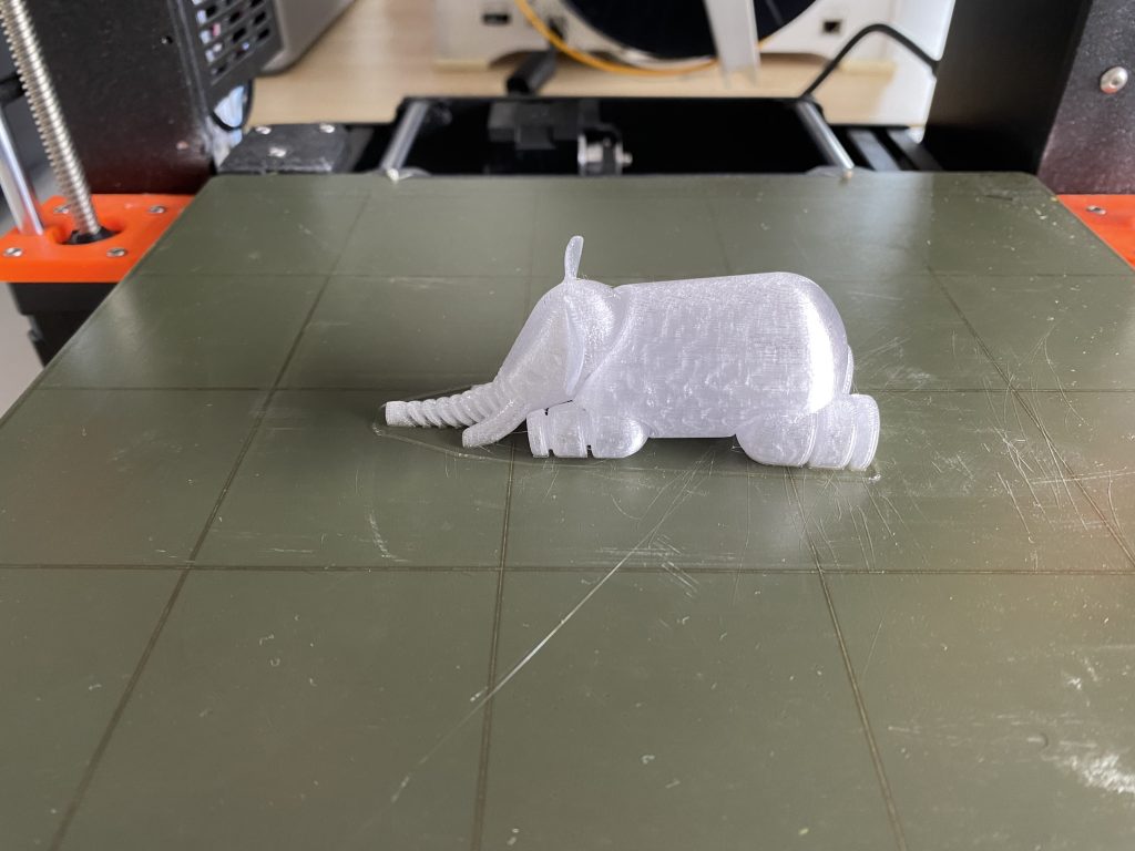 Ein weißer, 3D-gedruckter Elefant, der auf der Fertigungsplatte eines 3D-Druckers liegt